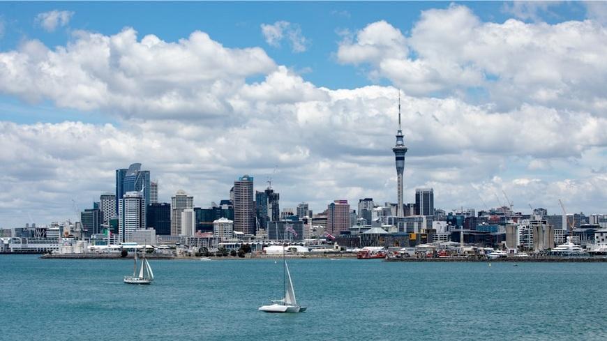 Sailboats near city buildings under white clouds and blue sky in Auckland, New Zealand during daytime.