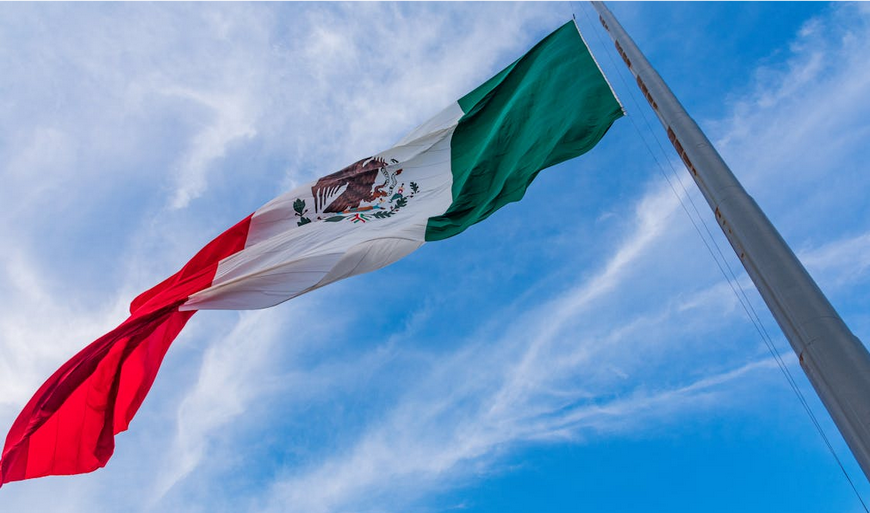Mexican flag flying against a bright blue sky