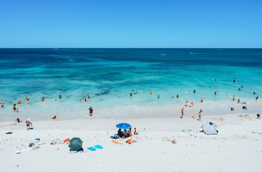 Beach visitors on the sand and in the water at Trigg Beach, Perth.